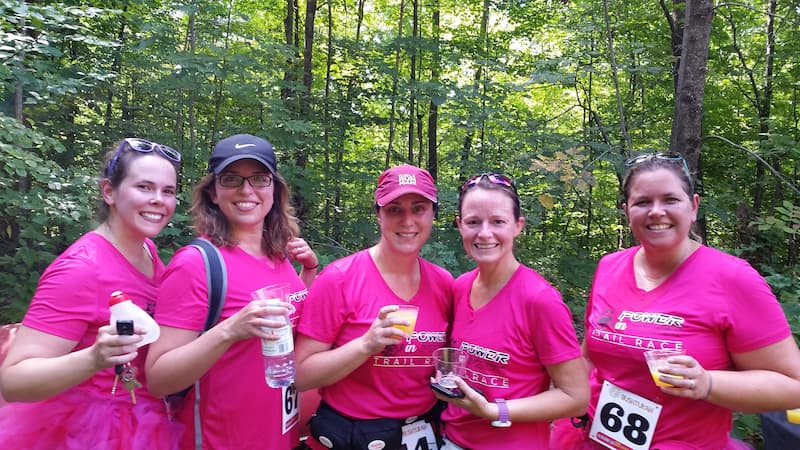 Five runners in pink shirts gather at a Power in Pink trail race